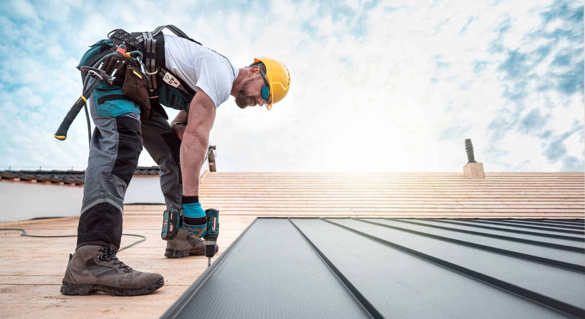 Reperatur.jpg Dachdecker mit Schutzhelm und Werkzeug bei der Montage einer neuen Dachverkleidung aus Metall bei Sonnenschein.