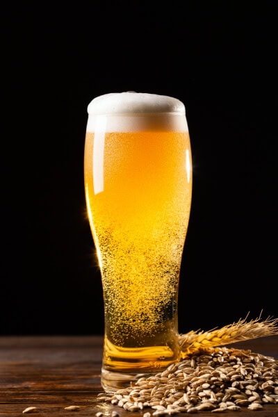 Erfrischendes Bier in einem Glas mit Schaum auf dunklem Hintergrund.