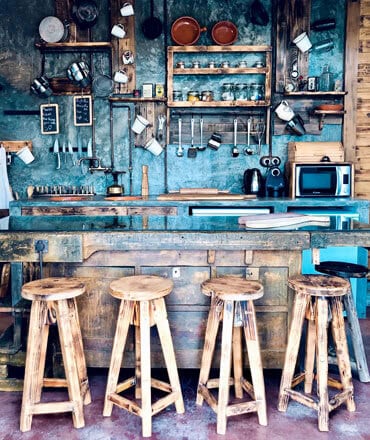 Gemütliche Bar in rustikalem Stil mit Holzskulpturen, Küchenutensilien und Einrichtungsdetails, perfekte Atmosphäre für gemütliche Treffen.