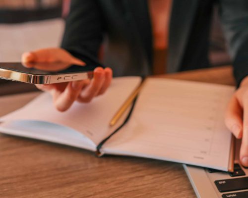 Businesswoman working on laptop and phone with notebook